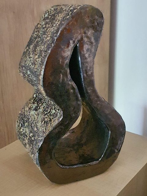 Pionowa falująca rzeźba ceramiczna z otworem, piaskowa faktura i ciemne wnętrze