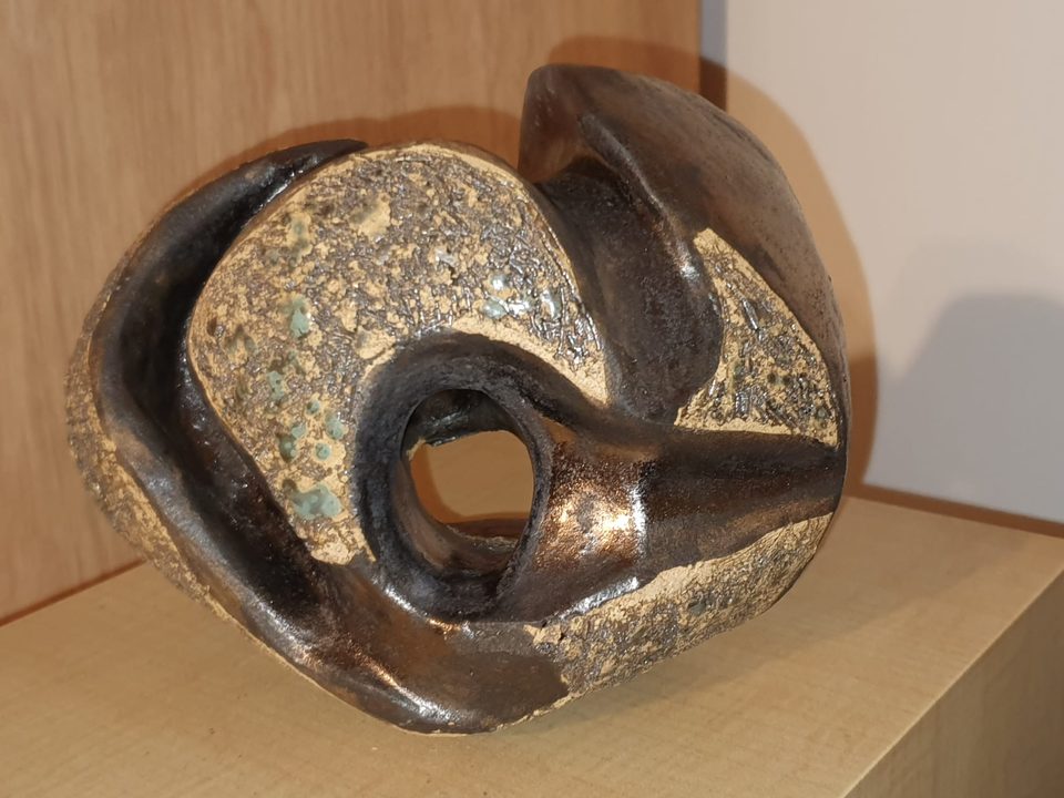 Opływowa rzeźba ceramiczna z prześwitem, jasna chropowata faktura i ciemne metaliczne szkliwo